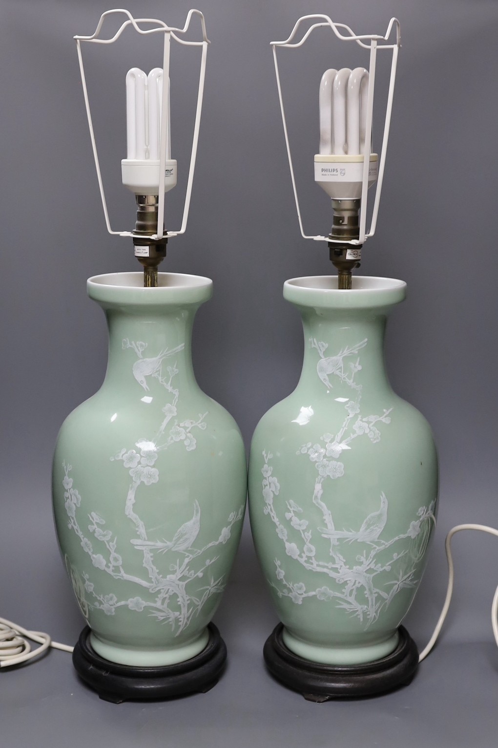 A pair of Chinese slip decorated celadon ground lamps, 40cms high including stands